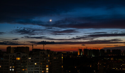 twilight city atmosphere, crescent moon over buildings in the dark, night city lights, clouds in the twilight sky