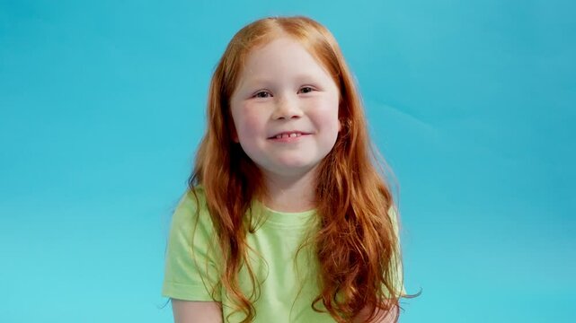 A Joyful Moment of a Young Girl Puffs Out her Cheeks Against a Vibrant Blue Background