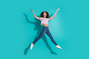 Obraz premium Full size photo of pretty young girl jump excited raise hands wear trendy striped outfit isolated on cyan color background