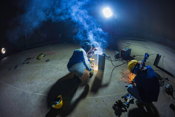 Welding male worker metal is part of machinery plate tank beam pipe construction flash spark inside