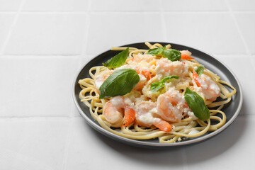 Tasty pasta with shrimps on white tiled table