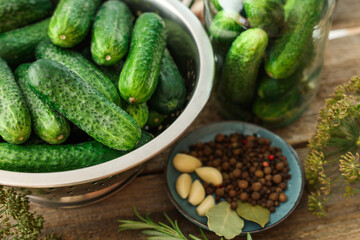 Fresh cucumbers, herbs and spices on wooden table, closeup. Preparation for pickling