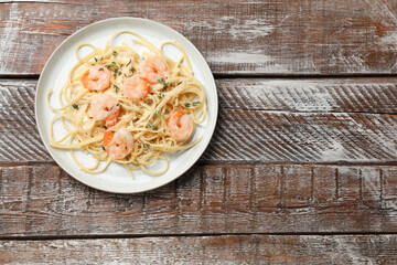 Delicious pasta with shrimps on wooden table, top view. Space for text