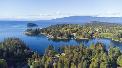 Fototapeta premium Sunshine Coast, British Columbia from the air. Bays and island of Madeira Park with island an mountains and islands in the background. Trees cover the land and coastline 