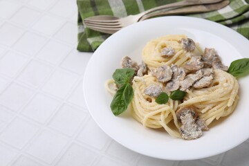 Delicious pasta with mushrooms and basil served on white tiled table, closeup. Space for text