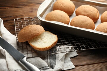 Fresh tasty buns and knife on wooden table