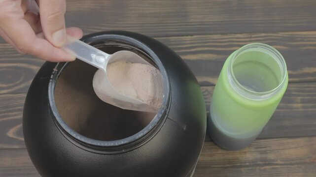 Mass gainer protein powder for muscle gain in black container. Healthy sports nutrition. Close up spoon for right dose.