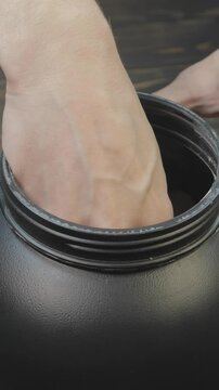 Vertical footage of a man taking mass gainer protein powder for muscle gain in black container. Healthy sports nutrition. Close up spoon for right dose.
