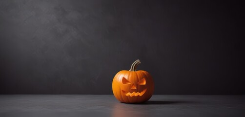 A carved pumpkin with a carved face sits on a dark surface, its orange hue contrasting with the surrounding darkness