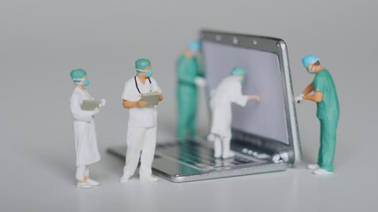 Miniature scene of doctor figurines placed on a laptop model acting as tech support specialists, providing professional assistance for issues or malfunctions in the system.