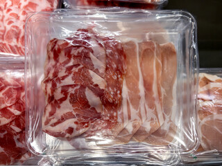 Mixed cold cuts in vacuum-packed plastic tray, slices of ham and salami and bacon slices © framarzo