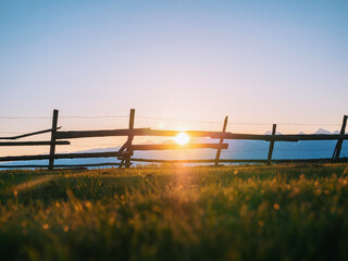 Wooden fence silhouetted against a mountain range at sunset