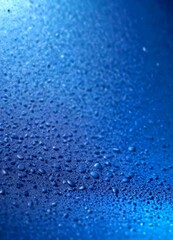 Water droplets on a dark blue surface, creating a textured and reflective effect