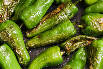 Pimientos de Padron background. Green peppers frying on a black pan. Cooking a Spanish delicacy,...
