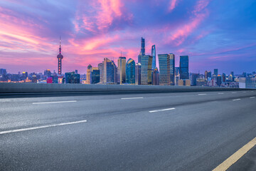 Naklejka premium Empty asphalt road and cityscape with skyline in modern city at sunset