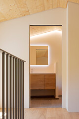 Detail of the bedroom, where you can see the door leading to the en-suite bathroom, parquet flooring. On the left is the railing of the staircase leading to the lower floor.