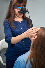 Optometrist inspecting patients head with hands during eye exam