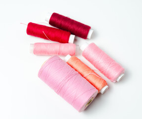Pink and red thread spools on white background.