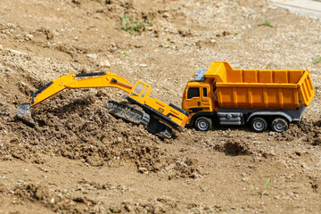 Toy cars in the sandbox. Toy dump truck and excavator.