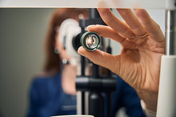 Optometrist adjusting slit lamp lens for examination