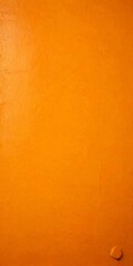 a close-up view textured orange wall, with a small circular hole in the bottom right corner