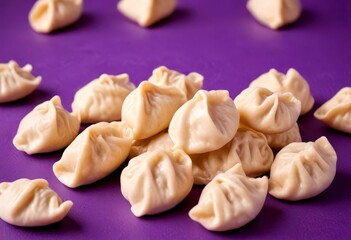 A pile of light-colored, round dumplings or buns is scattered on a purple background