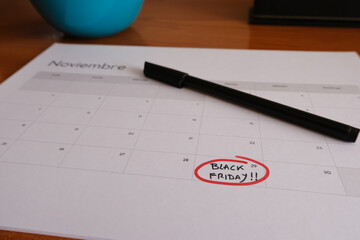 November calendar on a desk, with the last Friday of the month circled in red. Inside it are written the words Black Friday. Next to it is a black marker.