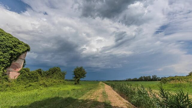 timelapse di media durata con inquadratura ampia su di una zona rurale di campagna, in pianura, nell'Italia nord orientale, di giorno, in estate, durante il passaggio di un temporale