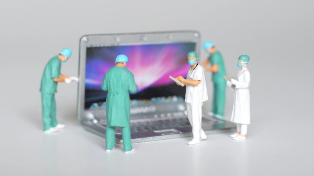 Kyiv, Ukraine - September 11, 2024: Group of miniature doctor figurines work on a laptop, illustrating the removal of malware and viruses, highlighting software protection and device health. - Powered by Adobe