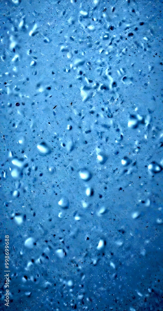 Poster a close-up view textured surface with numerous small, round water droplets scattered across it, creating a sense of depth and texture