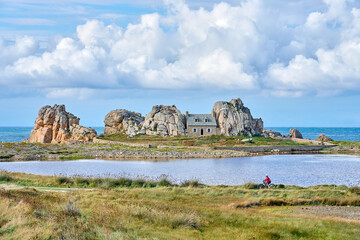 nice senior woman cycling with her electric mountain bike at the rocky rose granite coast of Le...