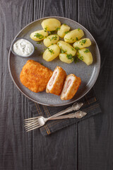French traditional cuisine chicken cordon bleu with new potatoes and cream sauce closeup on the plate on the table. Vertical top view from above