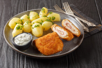 Tasty Chicken Cordon Bleu served with new potatoes and cream sauce closeup on the plate on the...