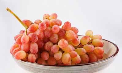 A juicy beautiful bunch of grapes lies in a plate.