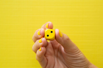 Woman's hand holding a yellow die with the number two on it