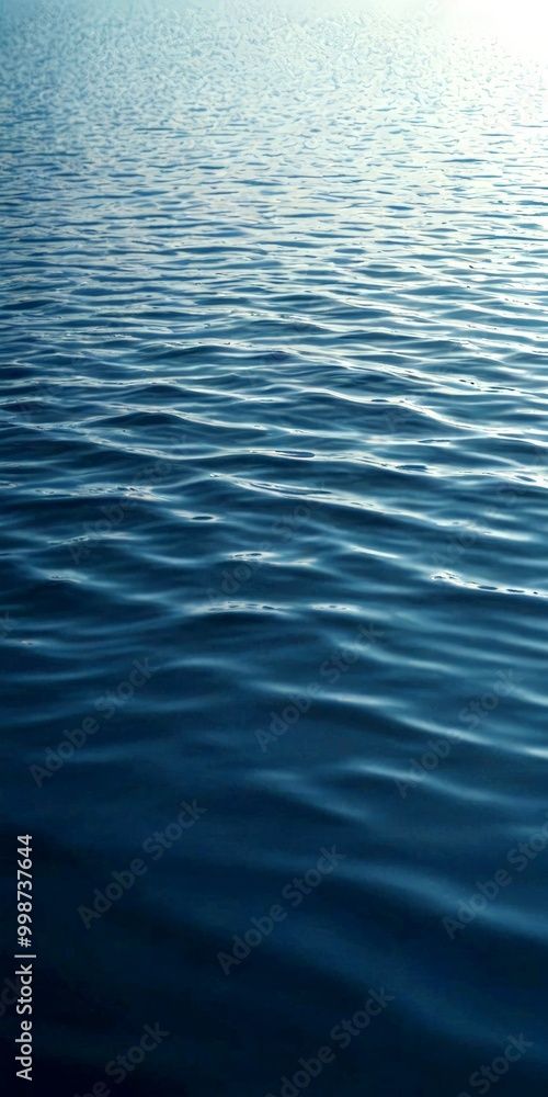 Poster a serene body of water with rippling blue-green waves, captured from a low angle that emphasizes the