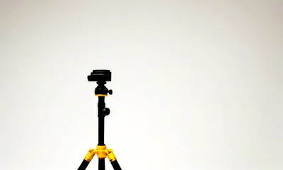 A black and yellow tripod stands against a plain white background