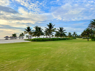 Beach with coconut trees, green grass and blue sky at Vinpearl resort and golf Nam Hoi An
