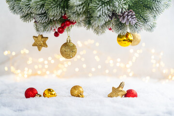 Christmas Holiday background with snow, fir tree and decorations with christmas light behind. Christmas red, white and golden balls on a winter festive background.