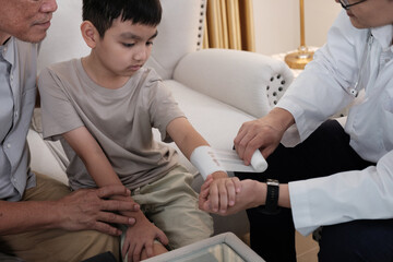 The doctor treats a wound on a boy's arm at home