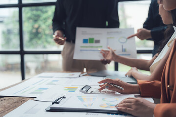 Business Analysis: A team of professionals collaborate on a project, examining charts and graphs, and using a calculator to analyze data.