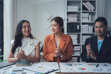 Business Team Collaboration:  A diverse team of Asian business professionals sits around a table, engaged in a collaborative discussion, showcasing teamwork and success.  