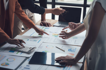 Strategic Collaboration: A team of diverse professionals huddle around a table, deeply engaged in...