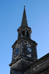 Old Church with Spire and Clock seen from below against Blue Sky 
