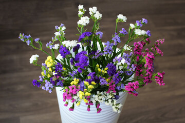 Bouquet of multicolored flowers in a vase (Limonium sinuatum, Statice sinuata) on a green background