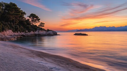 Obraz premium Sunset paints the sky in hues of gold and rose, casting its glow upon the tranquil sea. The gentle waves caress the sandy shore, reflecting the vibrant colors above. Soft sands stretch endlessly