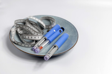 Naklejka premium Ozempic Insulin injection pen for diabetics and weight loss on a plate with a measuring tape
