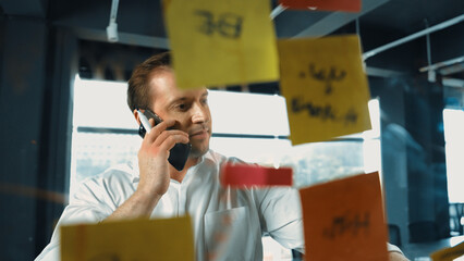 Professional businessman making phone call to customers while looking at marketing strategy idea...