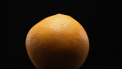 Macrography, the intricate texture of an orange against a striking black background steals the spotlight. Close-up shot captures the unique patterns and details of the orange's surface. Comestible.