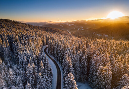 Aerial view of a road winding through a forest in the winter 